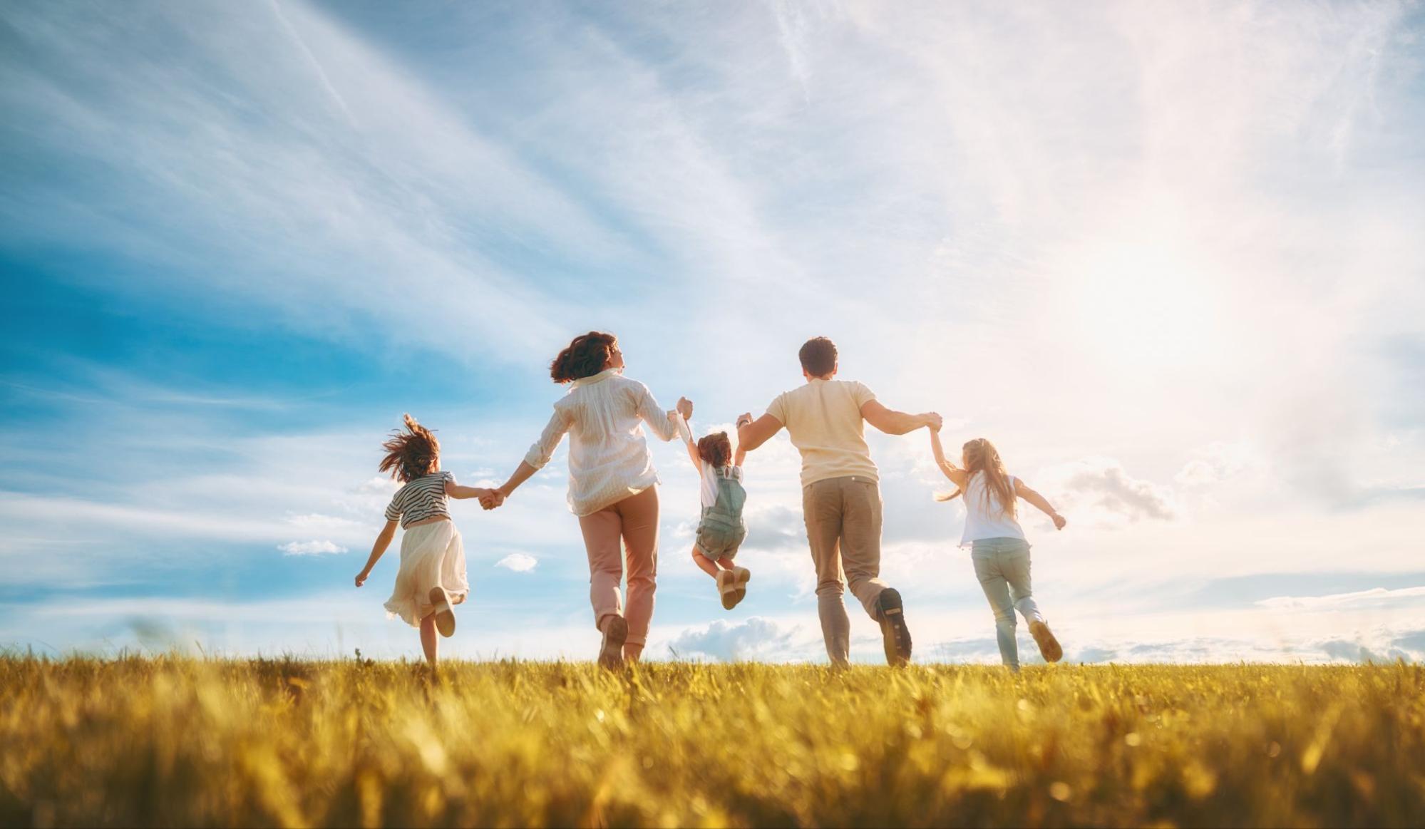 Family running together across a sunny field